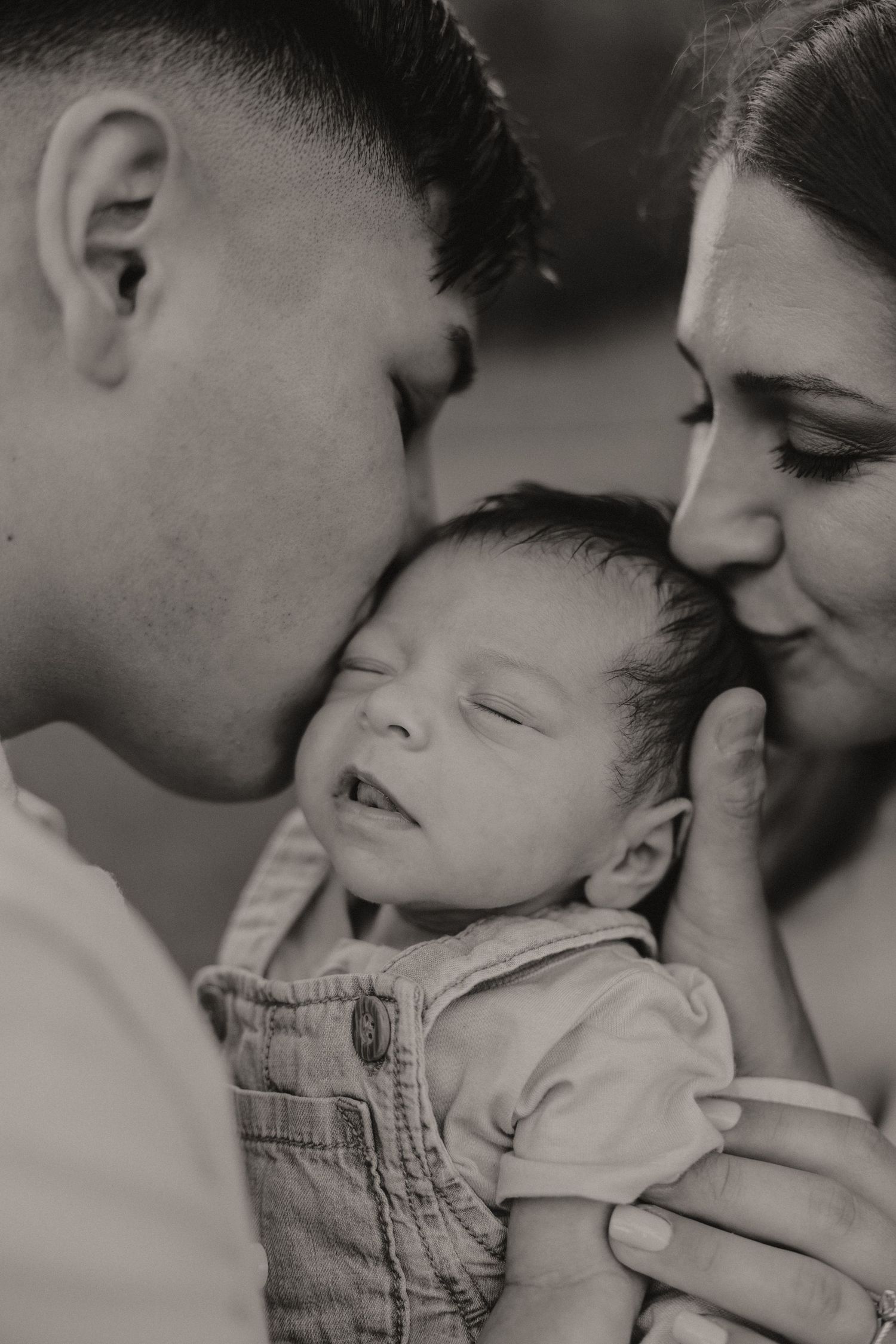 Intimate black and white family portrait series showing tender moments with a baby.