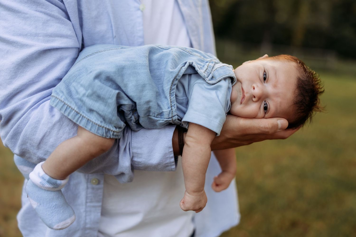 Series of gentle hands holding and supporting a sleeping baby in denim.