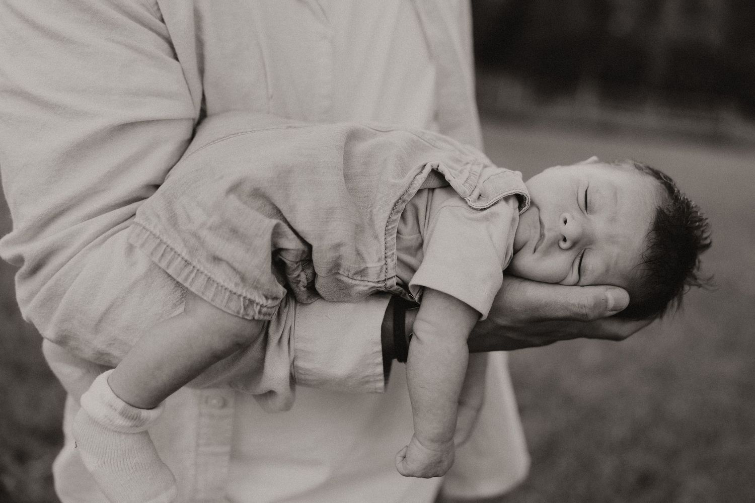 Black and white series showing careful hands cradling a sleeping infant.