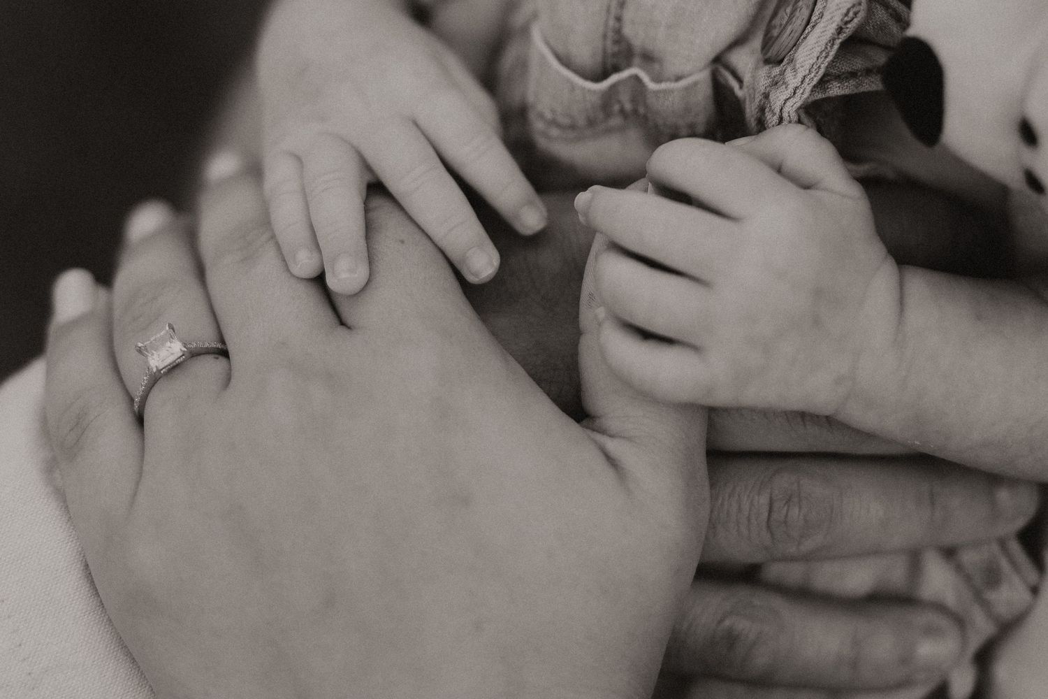 Intimate black and white close-up of gentle hands cradling a newborn.