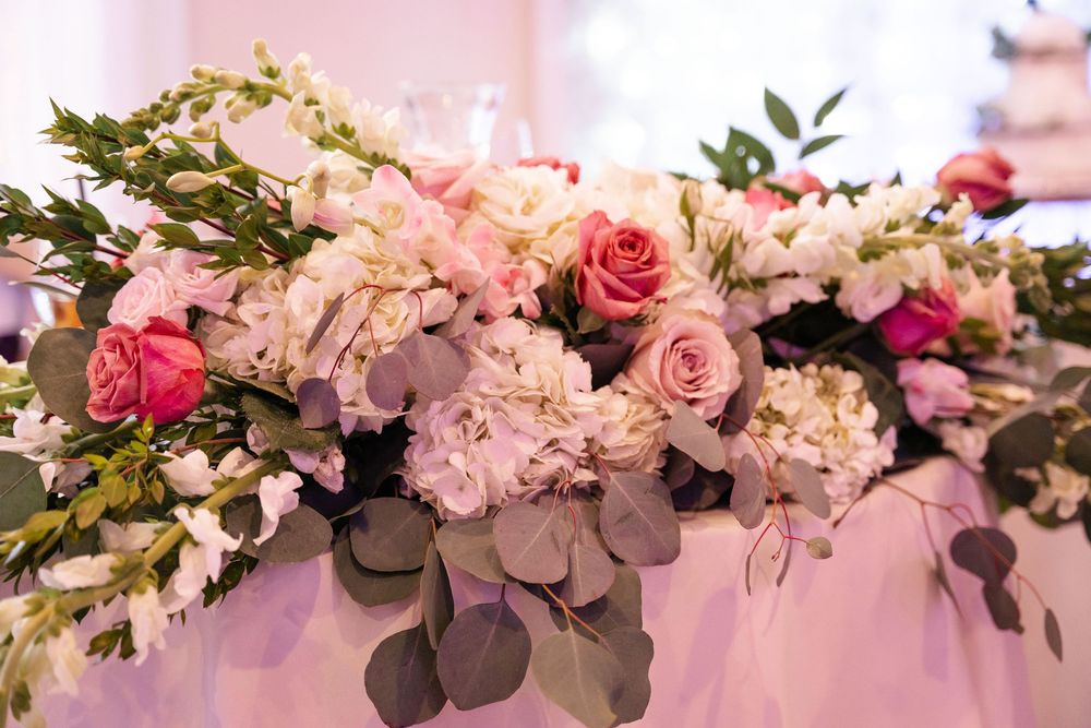 Elegant floral wedding decor featuring pink roses, white hydrangeas and eucalyptus leaves arranged in a cascading design.