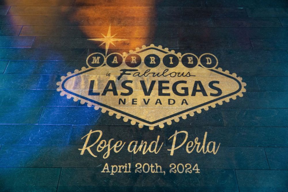 A blue and gold themed wedding invitation design featuring the iconic Las Vegas welcome sign and decorative text.