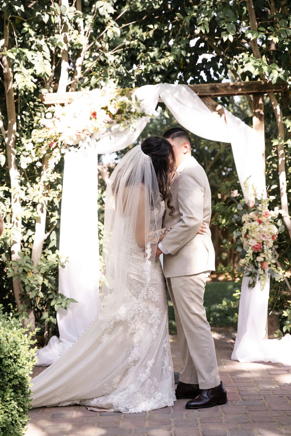 A romantic wedding sequence shows a couple in white sharing intimate moments under a garden pergola decorated with flowers.