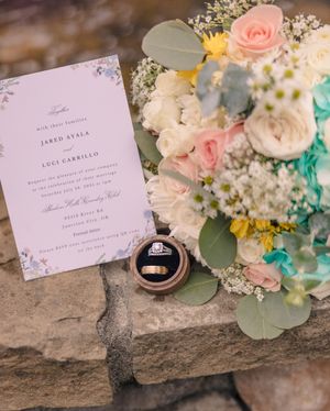 Wedding stationery and rings styled with delicate pink and white floral arrangements.