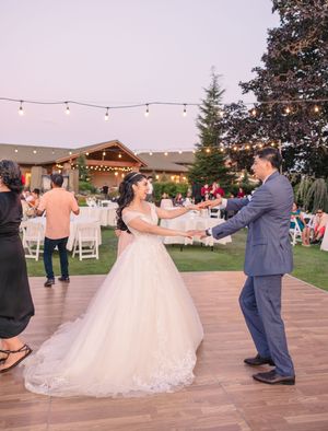 Wedding couple dancing on an outdoor deck decorated with string lights.