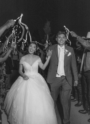 Black and white photo of wedding guests dancing and celebrating at an outdoor reception.