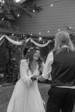 Black and white photo of joyful dancing at an outdoor wedding reception.