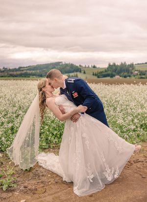 Romantic pose in a blooming white flower field against rolling hills.
