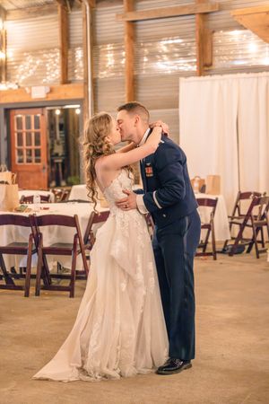 A romantic first dance moment between newlyweds in a rustic indoor venue.