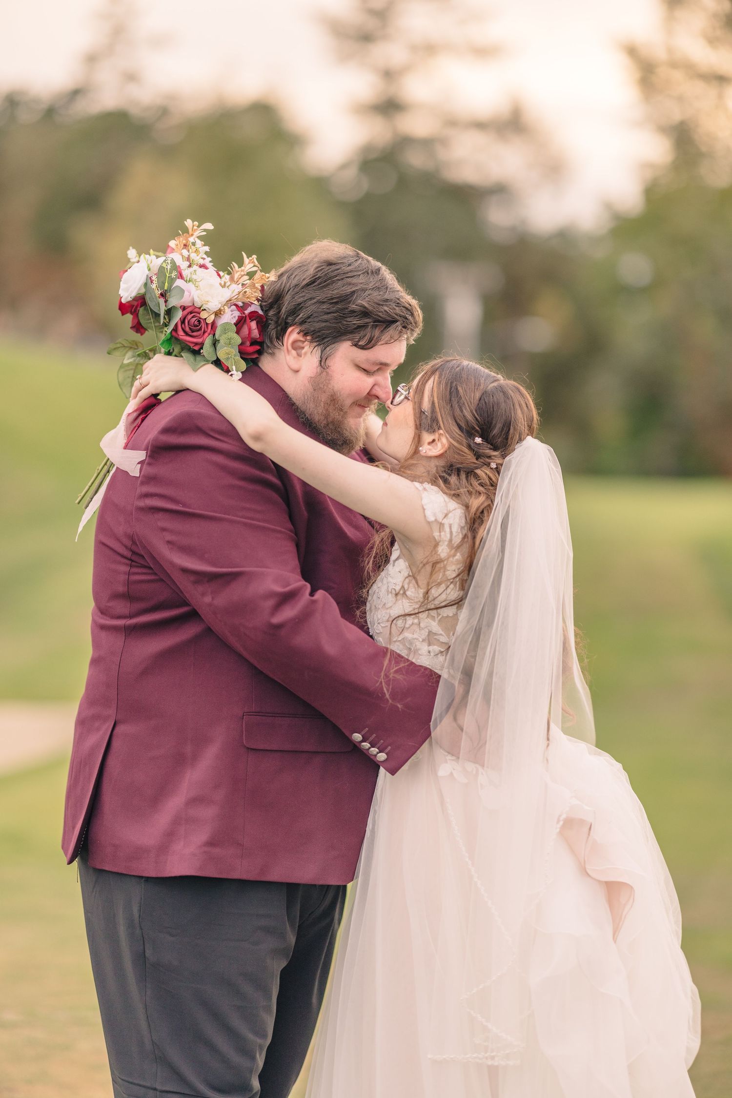 A tender embrace between newlyweds during sunset in an outdoor garden setting.