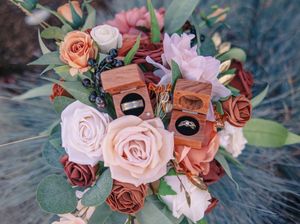 Beautiful wedding bouquet with coral and pink roses arranged artistically on a dark background.