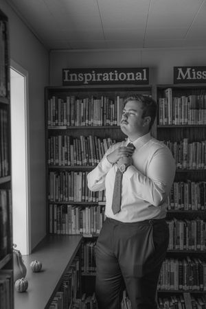 Black and white photo in a library showing intimate moments between a couple.