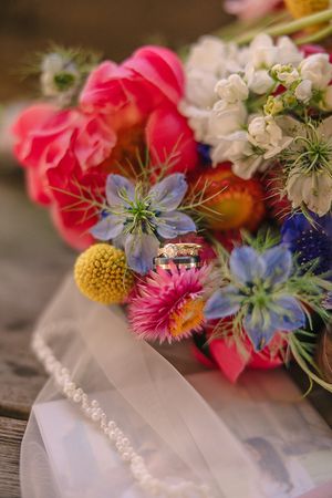 Colorful wedding bouquet with pink, blue and yellow flowers displayed on rustic wood.