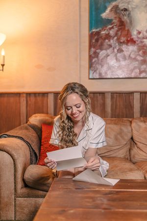 Cozy indoor scene showing someone reading letters on a brown leather couch.
