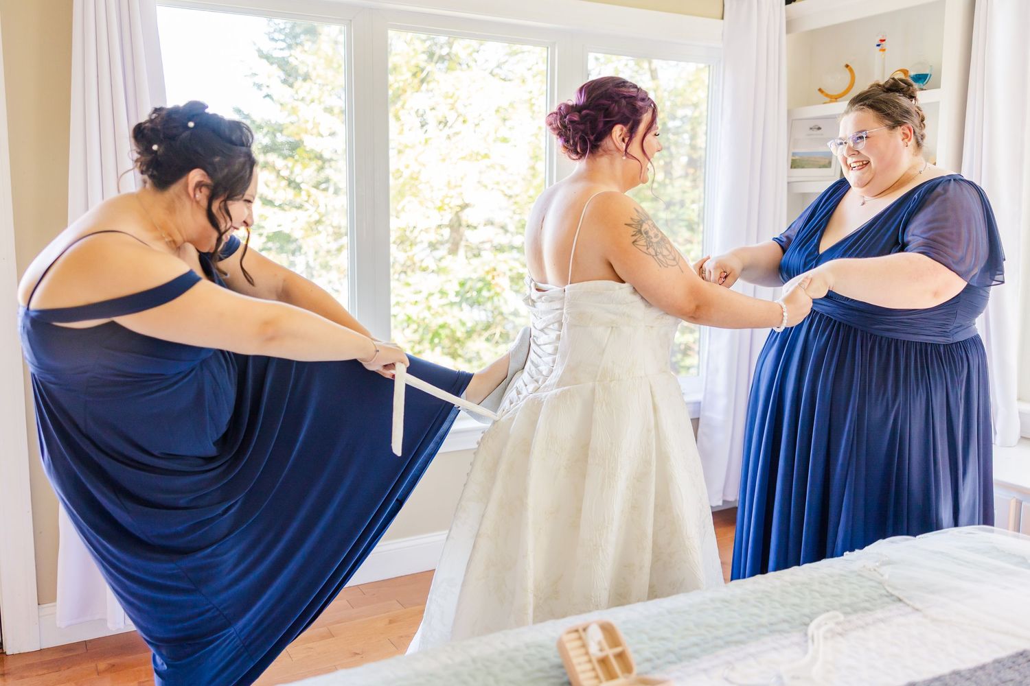 A collage of wedding party members in navy blue and white dresses getting ready in a sunlit room.