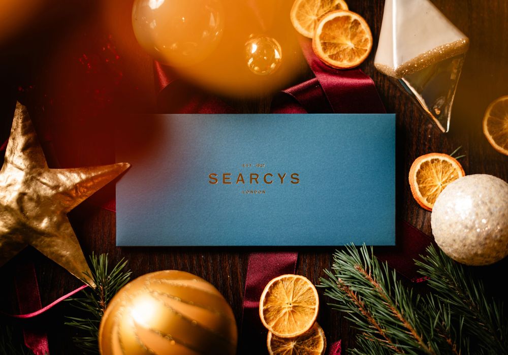 Festive holiday scene with dried orange slices, pine branches, and golden pumpkins illuminated by warm glowing lights.