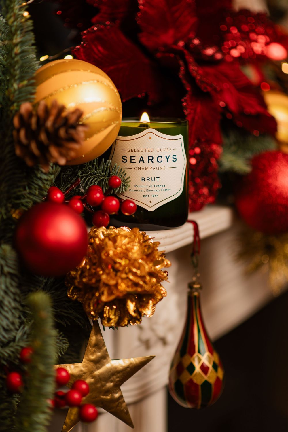 Close-up of elegant Christmas decorations featuring gold ornaments, red berries, and a bottle of Spearcys champagne.