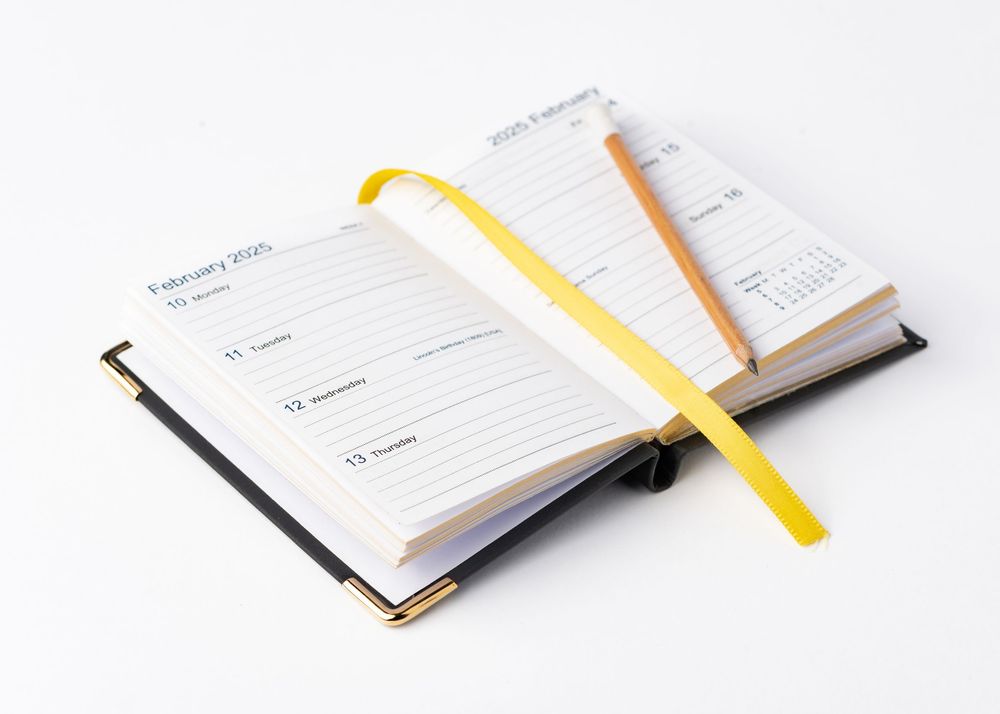 Open daily planner notebook with yellow bookmark ribbon on white background.