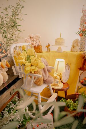 Yellow and white themed photo backdrop with floral arrangements and decorative elements.