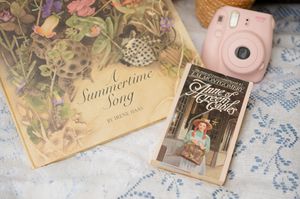 Decorative cards and vintage-style items arranged on a lace tablecloth for an outdoor picnic.