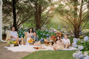Outdoor picnic scene under tall pine trees with white blankets and wicker baskets.