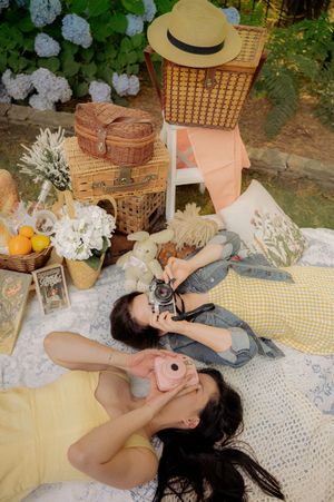 A dreamy summer picnic setup with vintage accessories and friends enjoying the outdoors.