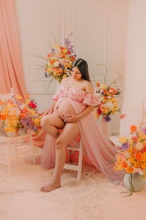 Ethereal maternity photography featuring soft pink tones and colorful flower arrangements.