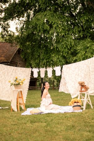 Peaceful outdoor maternity scene with vintage-style decor and hanging baby clothes.