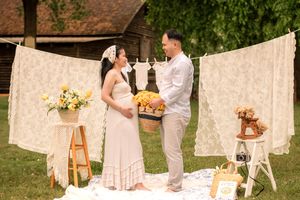 Romantic maternity photo session in a garden with white lace backdrops and vintage-style decorations.