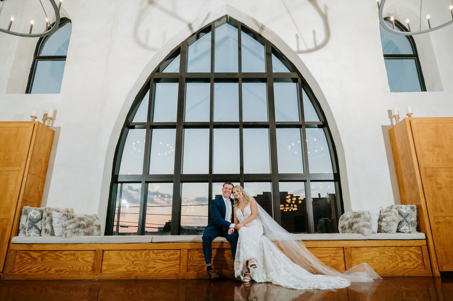 Elegant wedding venue interior with arched windows and white curtains creating a bright, romantic atmosphere.