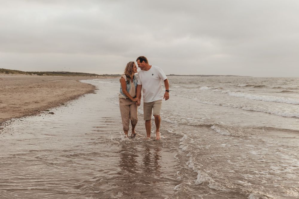 verliefde stel lopen hand in hand door de branding op het strand