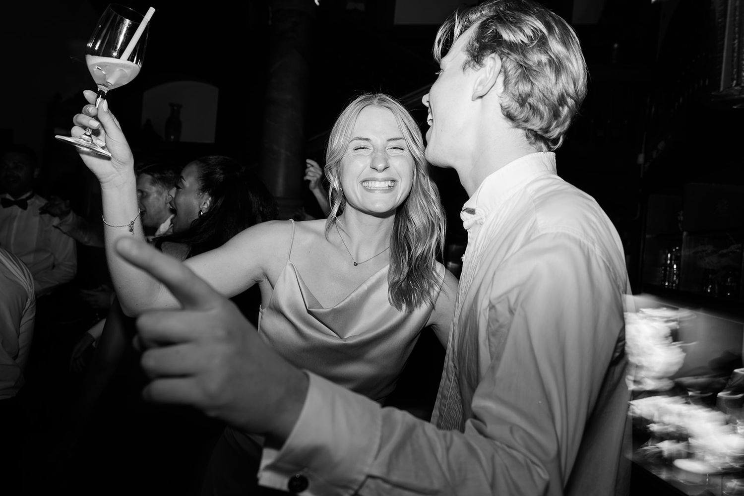 Black and white photo sequence showing people dancing and celebrating at a party in a dimly lit room.