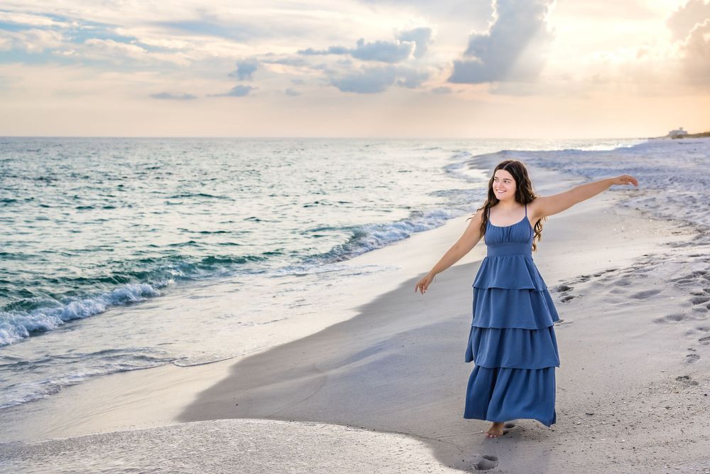 A series of beach photos showing someone in a blue dress walking and posing along the sandy shoreline at sunset.
