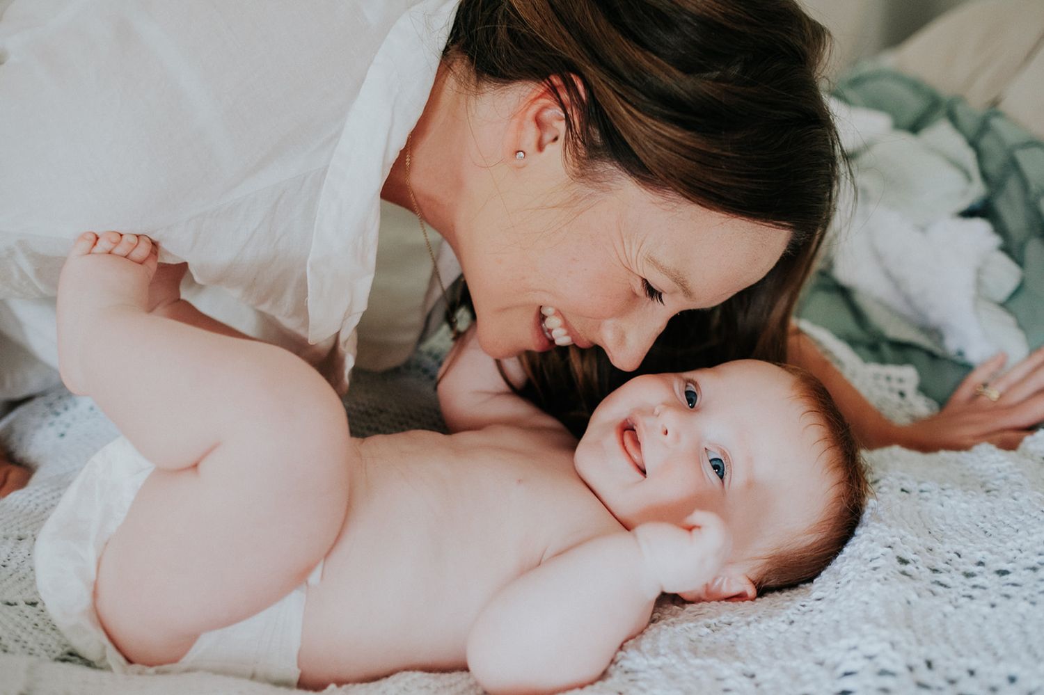 A tender black and white photo collage showing intimate moments between parent and baby on white bedding.