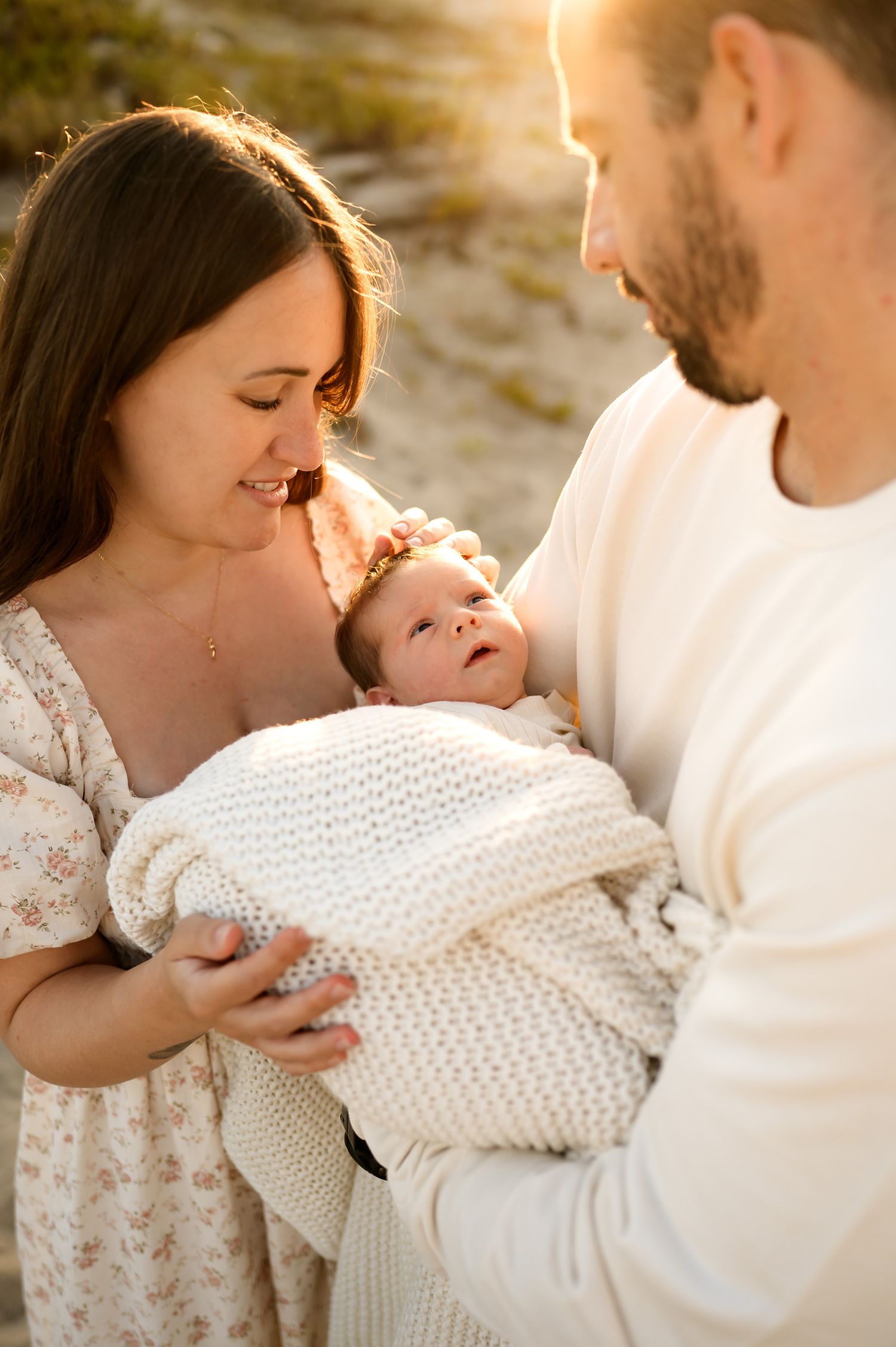 Carpinteria newborn beach photoshoot by Ventura and Santa Barbara photographer. Baby is bundled up in blanket in golden sun