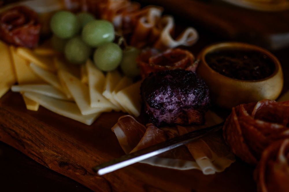 Elegant wedding reception charcuterie board with grapes and assorted meats.