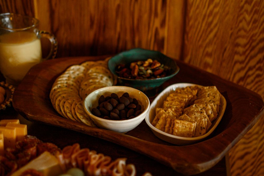 Charcuterie board with meats, cheeses, fruits and crackers displayed on dark wood surface.