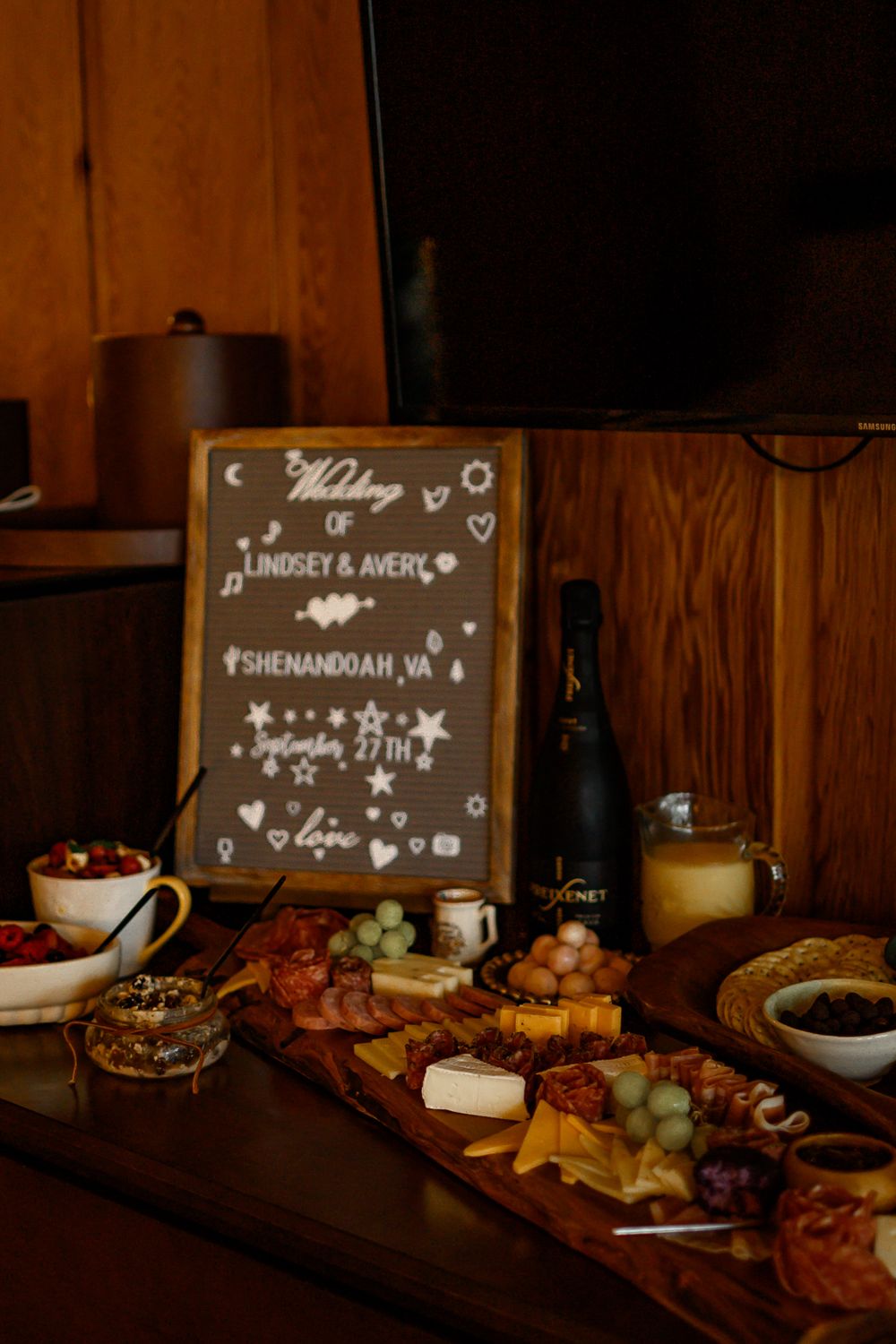 Dimly lit grazing table with decorative chalkboard signs and various appetizers.