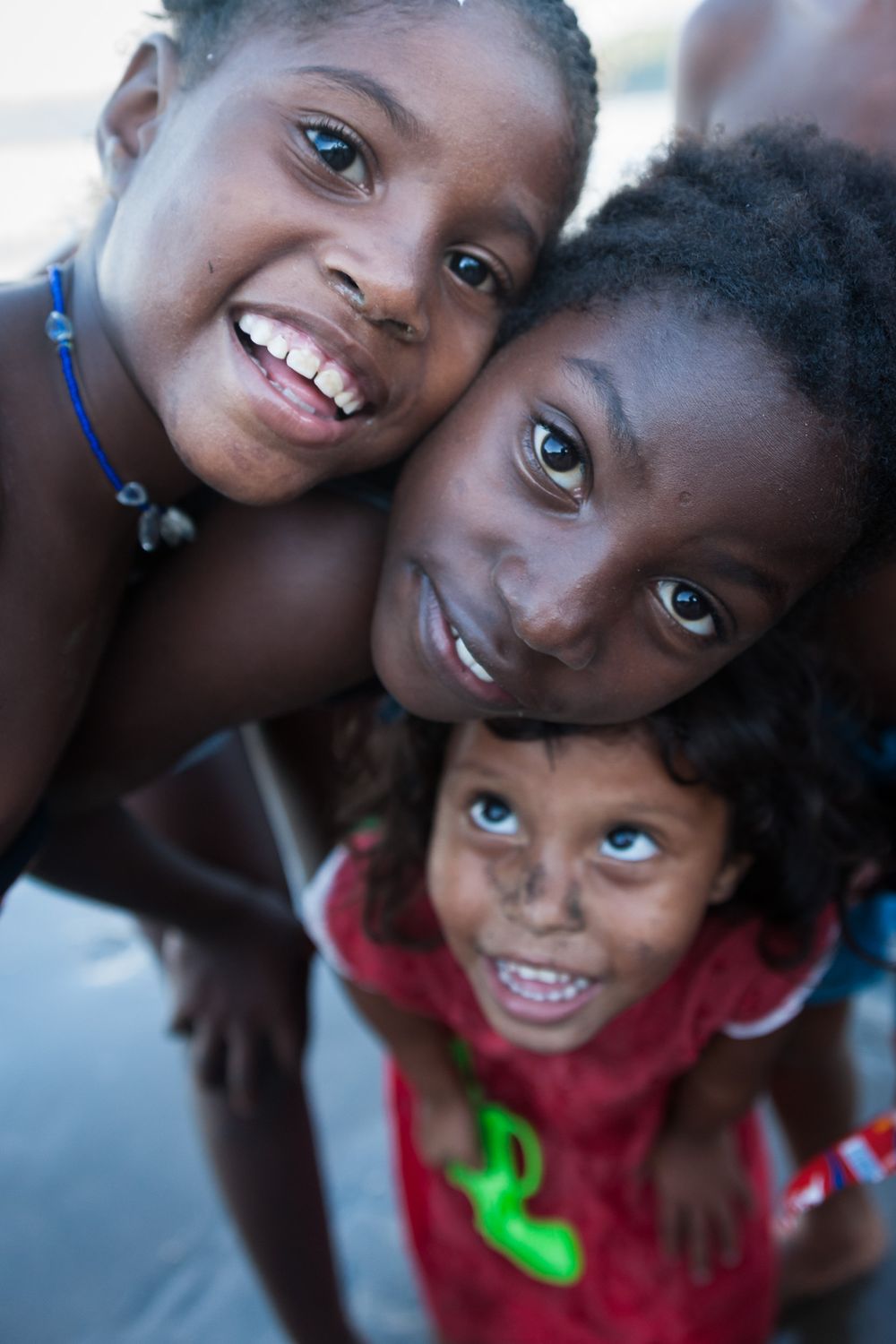 A sequence of three images showing joyful children looking up at the camera with bright smiles.