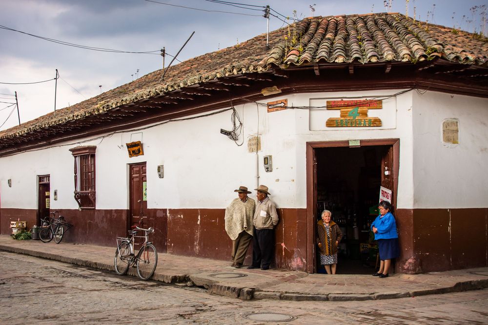 Colonial architecture with white walls and terracotta roofs lines the cobblestone street in a historic Latin American town.