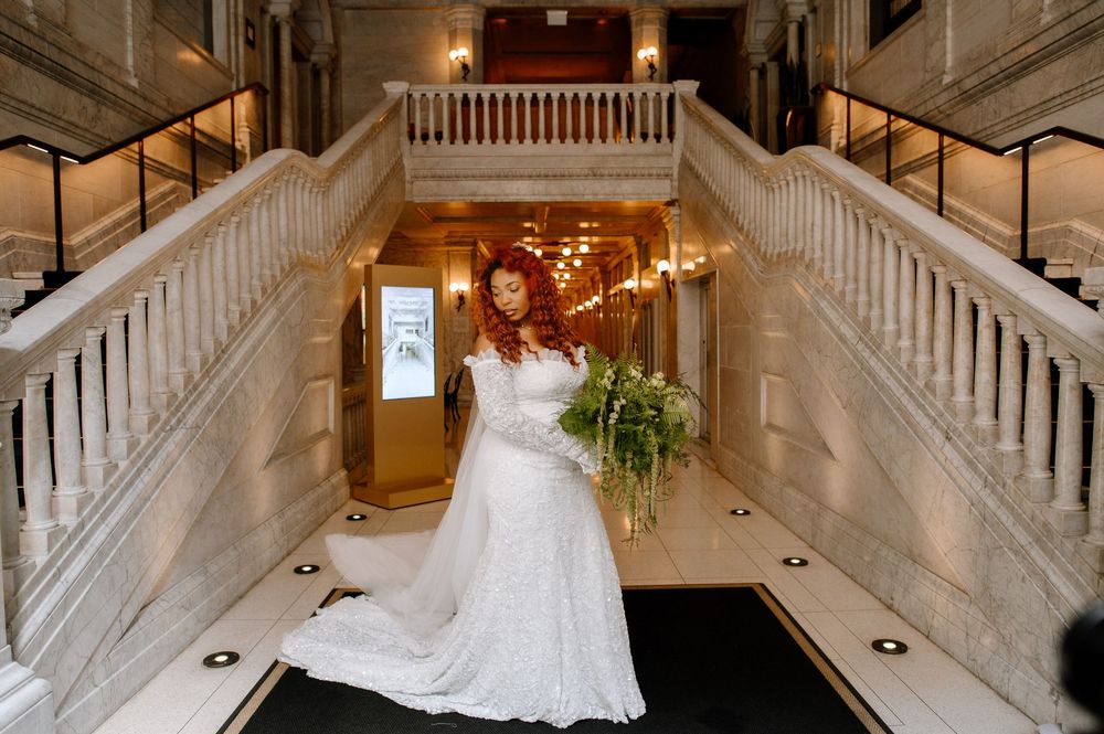 Bride descending majestic white marble staircase in luxurious wedding gown with flowing train.