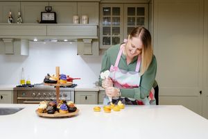 Person preparing food in a modern kitchen with stainless steel appliances and white cabinets.