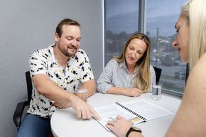 People seated at a conference table reviewing documents during a business meeting.