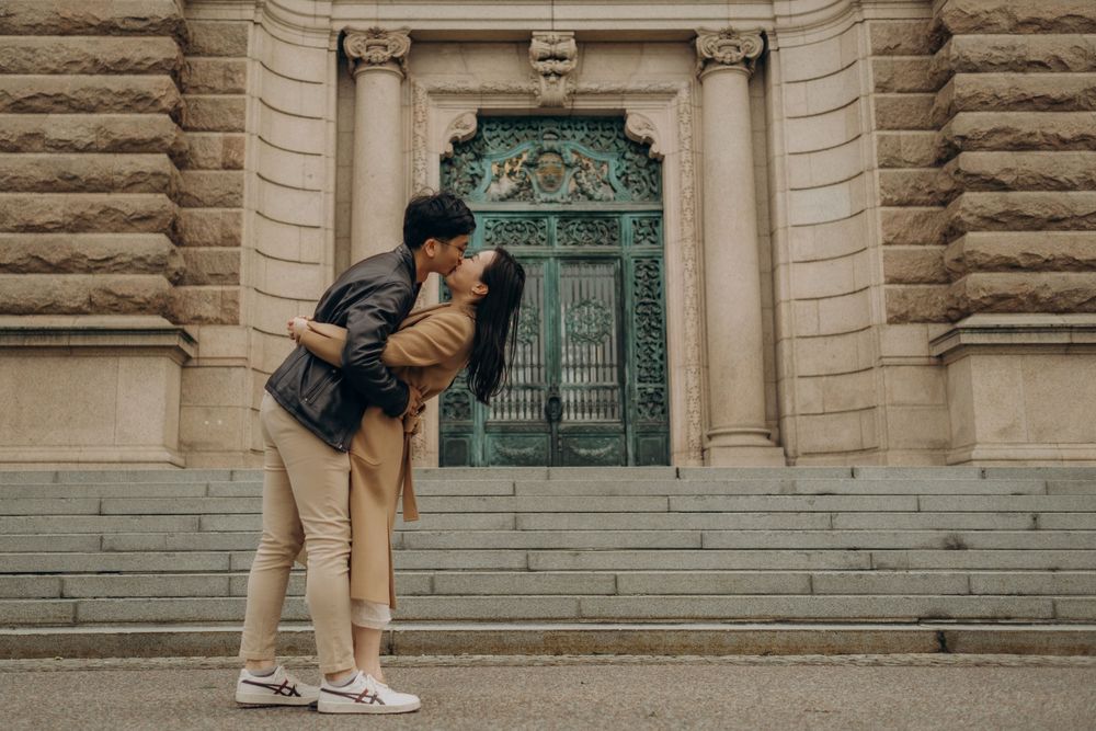couple kissing in front of Parliament House in Stockholm while being captured by English-speaking photographer in Stockholm