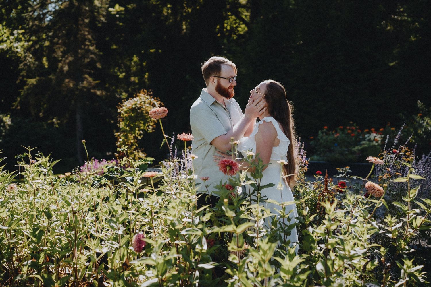 Couple sharing a tender moment in a blooming garden with vibrant summer flowers.