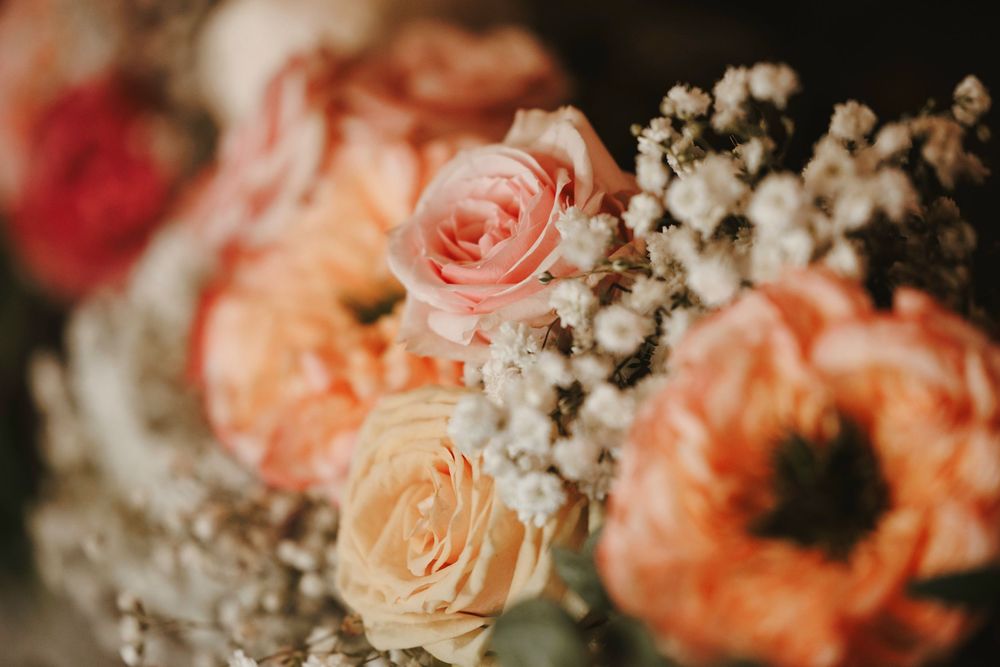 Close-up of a romantic bridal bouquet featuring peach and pink roses with delicate white baby's breath flowers.
