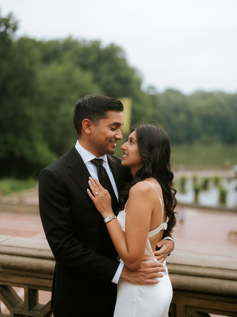 A romantic moment shared between a couple in formal attire by a waterfront.