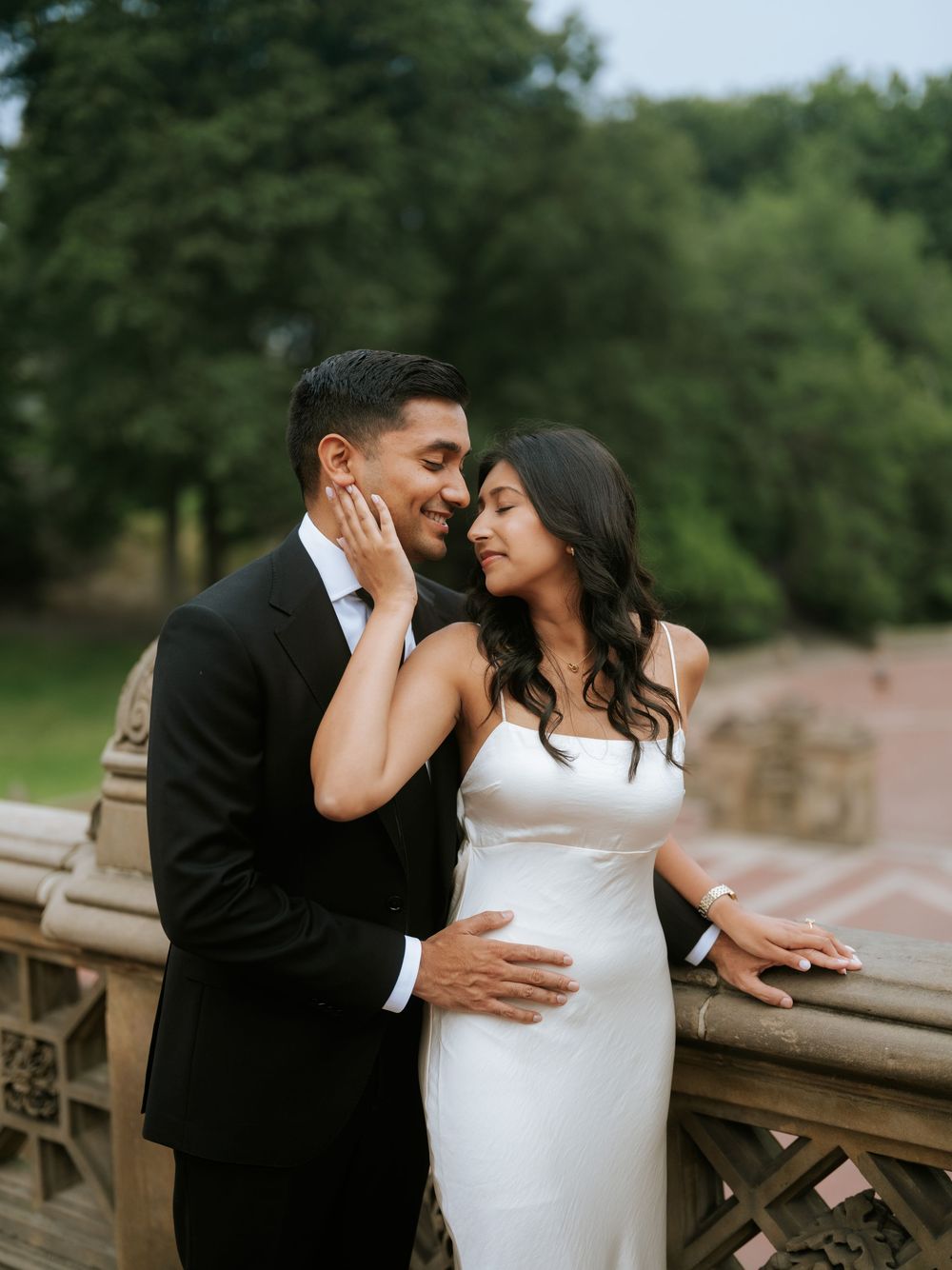 A couple in wedding attire shares an intimate moment on a deck.