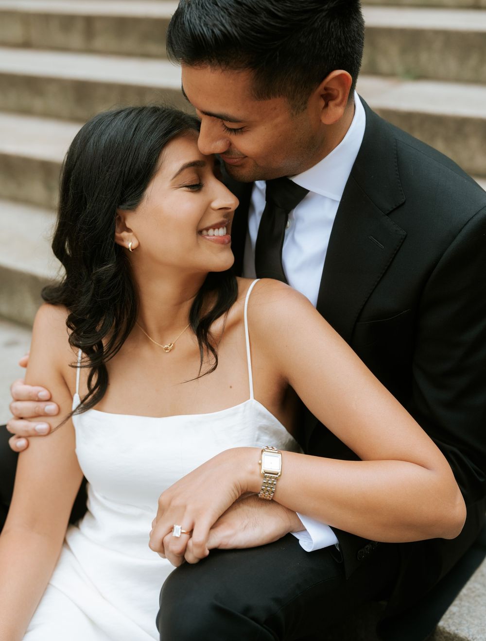 A romantic wedding portrait of a couple sharing an intimate moment on stone steps.