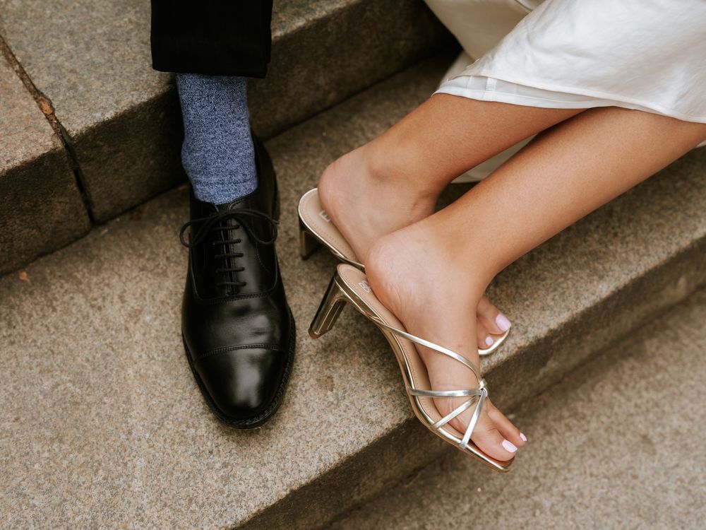 Close-up of formal shoes and heels on stone steps during an elegant photoshoot.